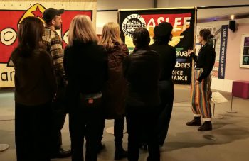 Image of A group of people on a tour facing colourful banners.