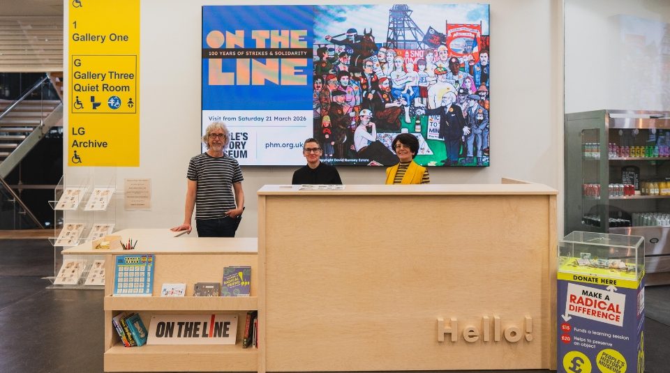 Image of Three people stood behind a museum welcome desk