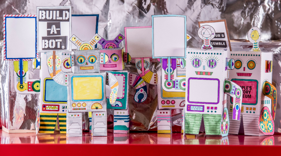 Image of Colour photograph of a crowd of mini robot models made from sheets of paper.