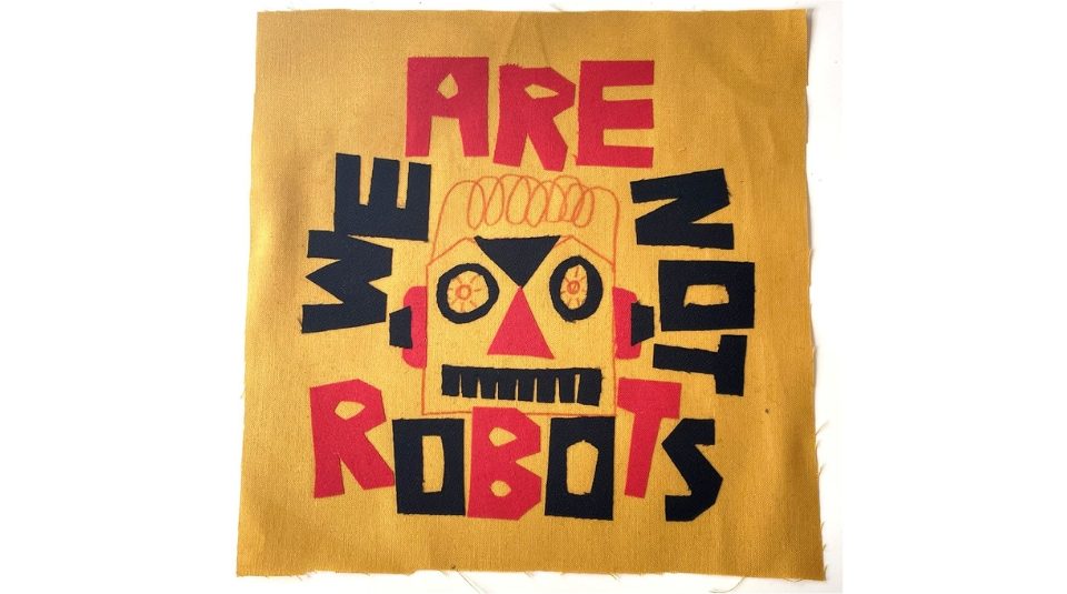 Image of A fabric sample. The red and black test reads WE ARE NOT ROBOTS