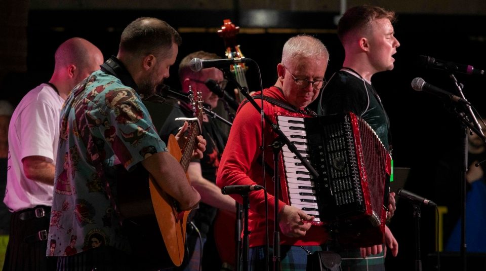 Image of Photograph of a five-member band performing with an accordion, guitar, and double bass.