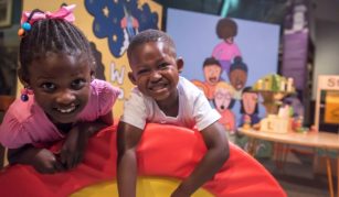 Image of Photograph of two children against a background of vibrant cartoon murals
