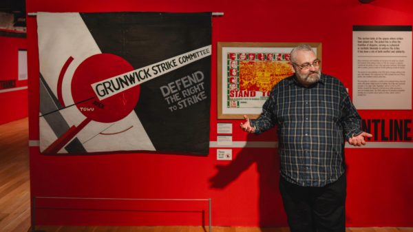 Image of A black and white banner with a geometric design including a large red circle, and text including: 'Grunwick Strike Committee, Defend The Right To Strike'.