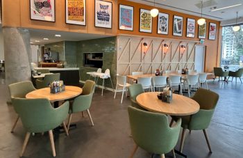 Image of Colour photograph of a café space with tables and chairs and vibrant artwork on the wall.