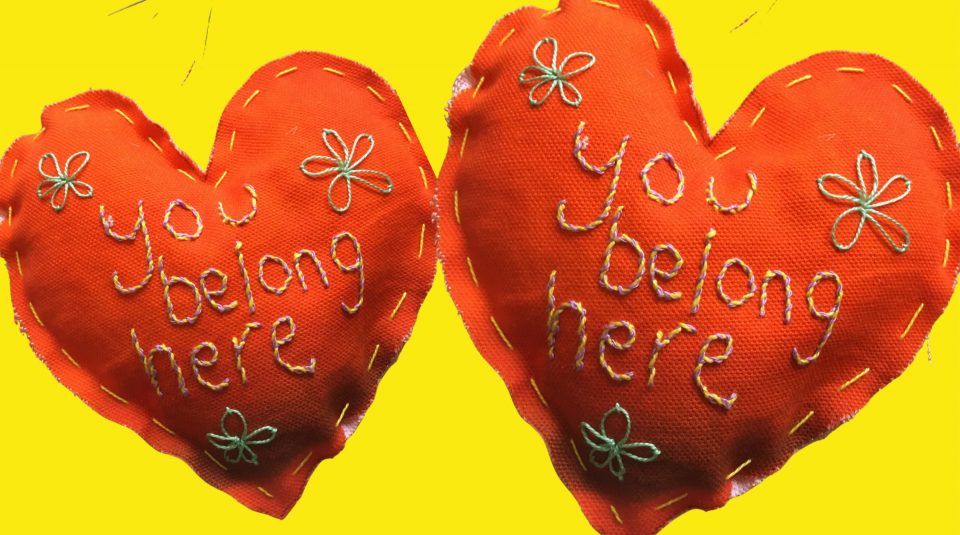 Image of Handstitched Orange stuffed heart, wording ‘You belong here’ 