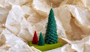 Image of Colour photograph of three Christmas tree shaped wax candles; one coloured red and two coloured dark green.