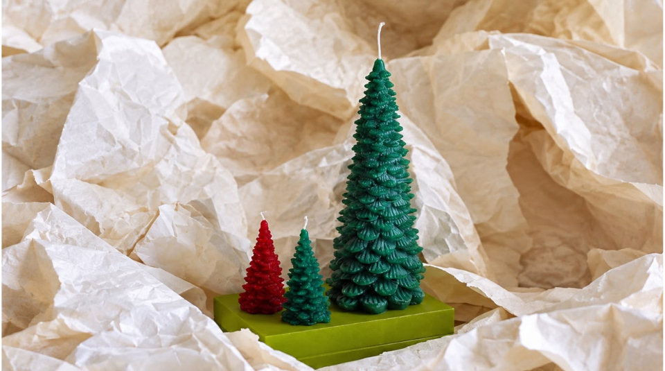 Image of Colour photograph of three Christmas tree shaped wax candles; one coloured red and two coloured dark green.